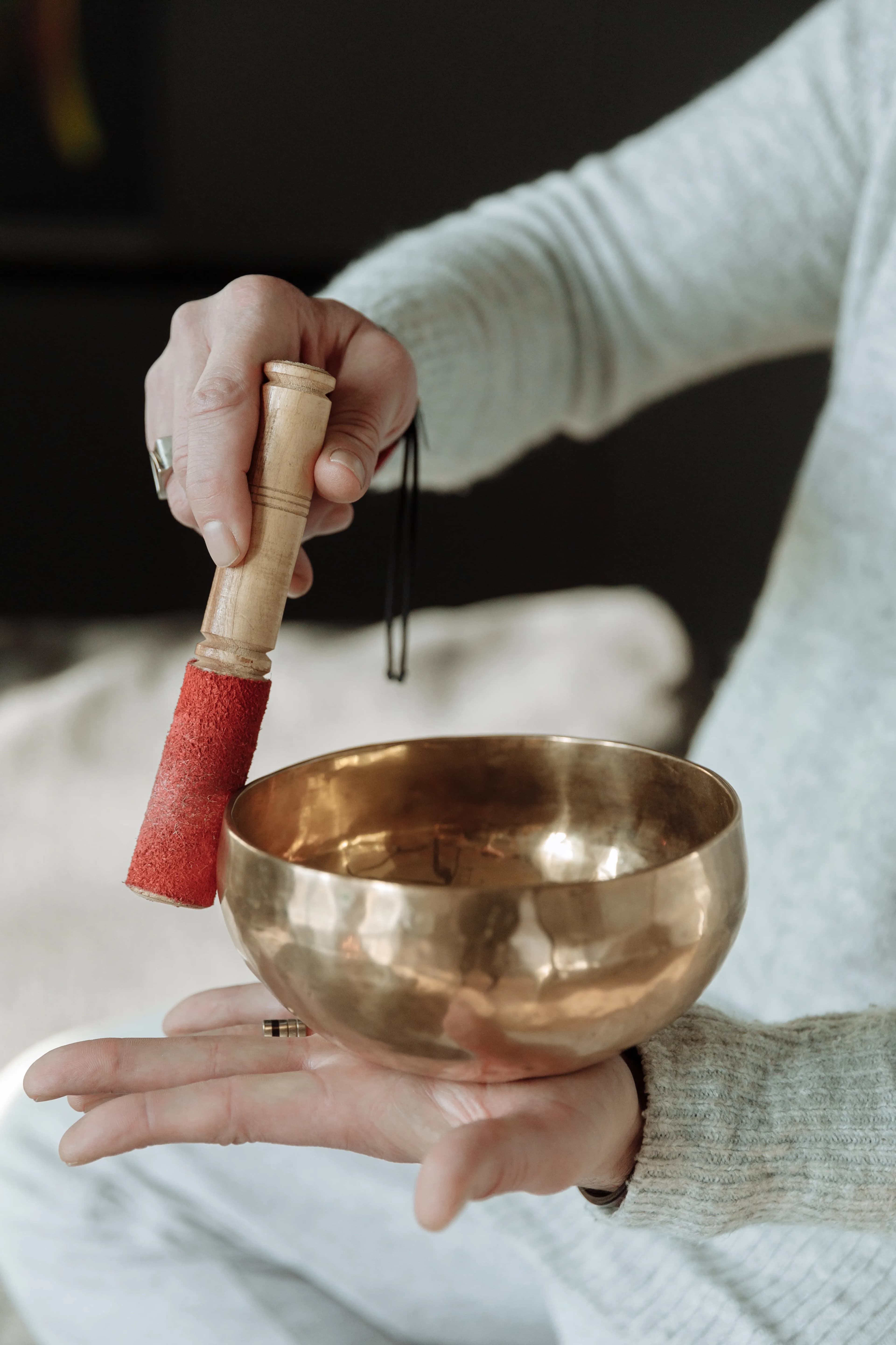 Person holding a brass singing bowl while choosing an instrument